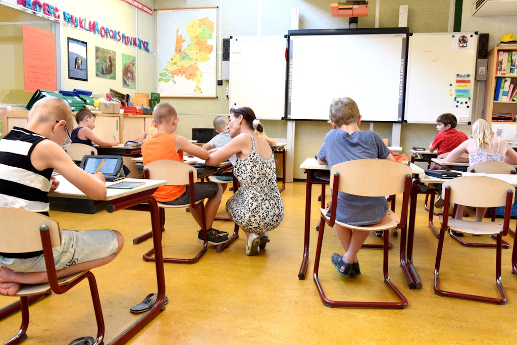 Children engaged in learning with a teacher in a bright classroom setting.